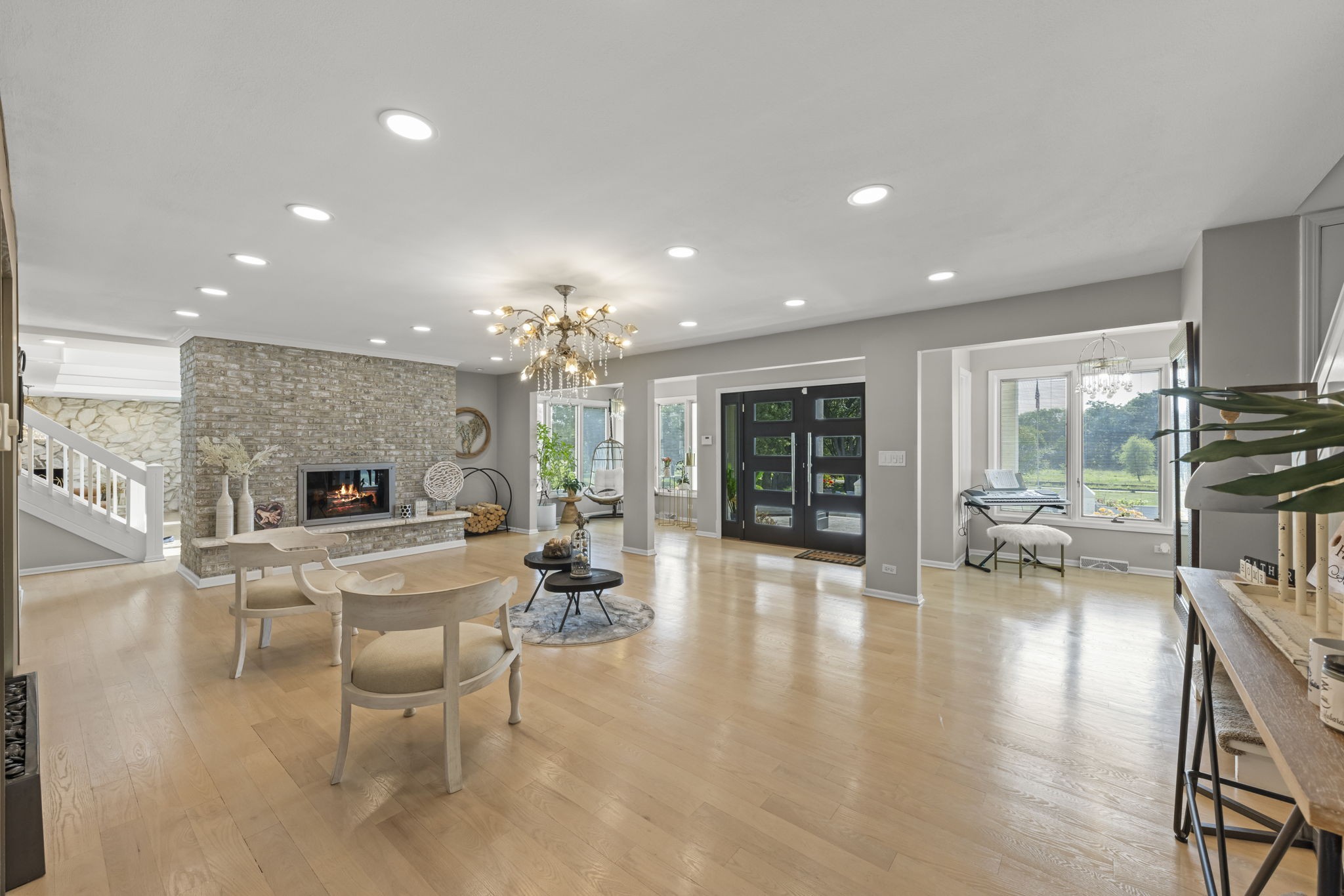Naperville IL luxury home formal living room at 23W735 Hobson Rd featuring two-story floor-to-ceiling stone fireplace, vaulted beam ceilings, and arched Pella windows