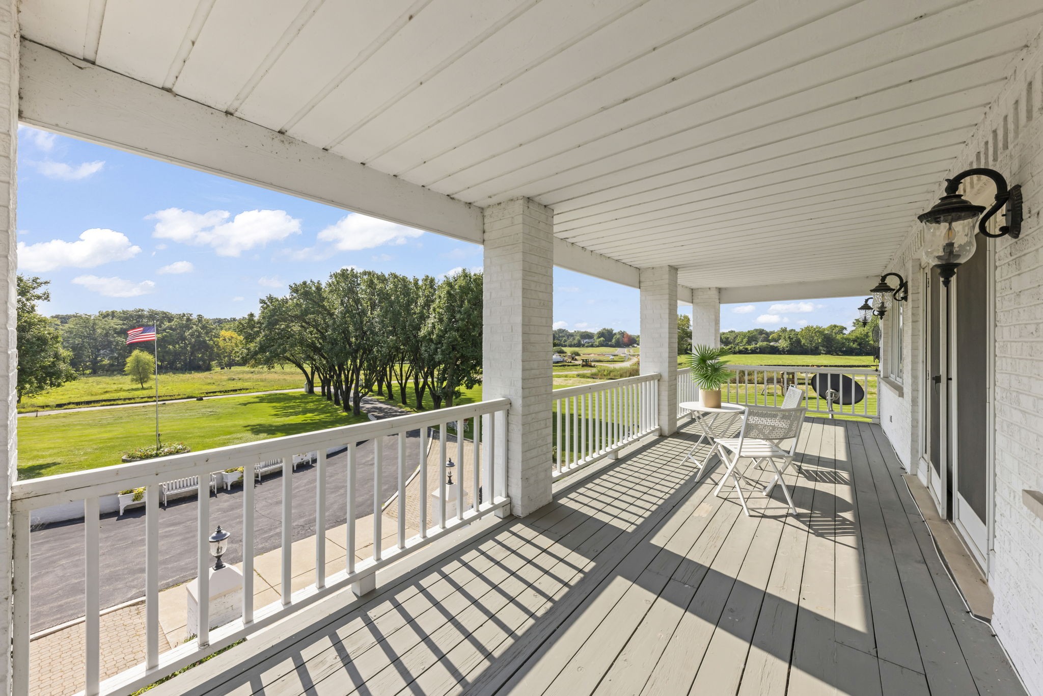 Naperville luxury real estate primary bedroom retreat at 23W735 Hobson Rd with double-sided fireplace, sitting room, and private covered balcony overlooking estate grounds